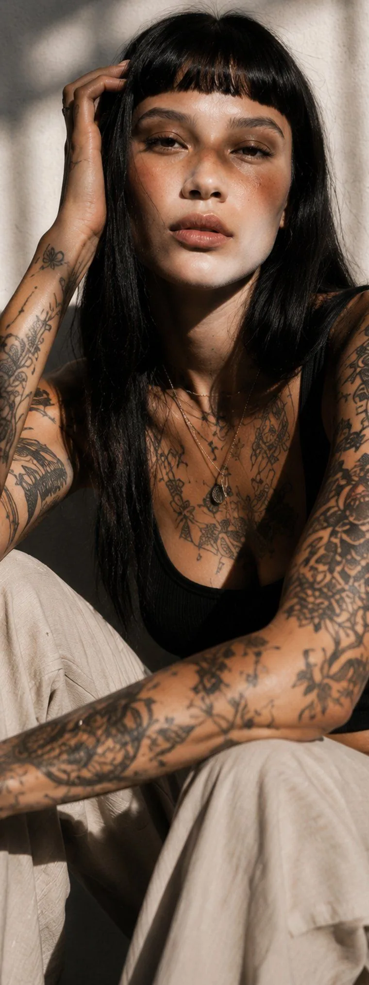 A woman with fine-line sleeve tattoos on both arms and across the chest